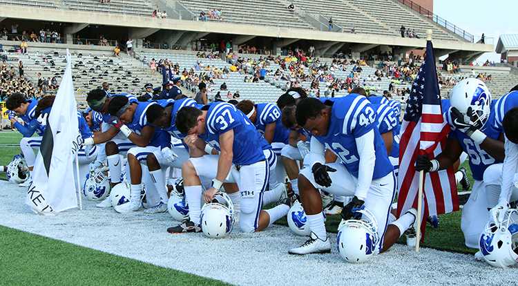 Cy Creek Cougars take a kneel during the National Anthem