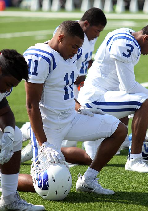 Senior Alex Williams kneels before the start of the game.