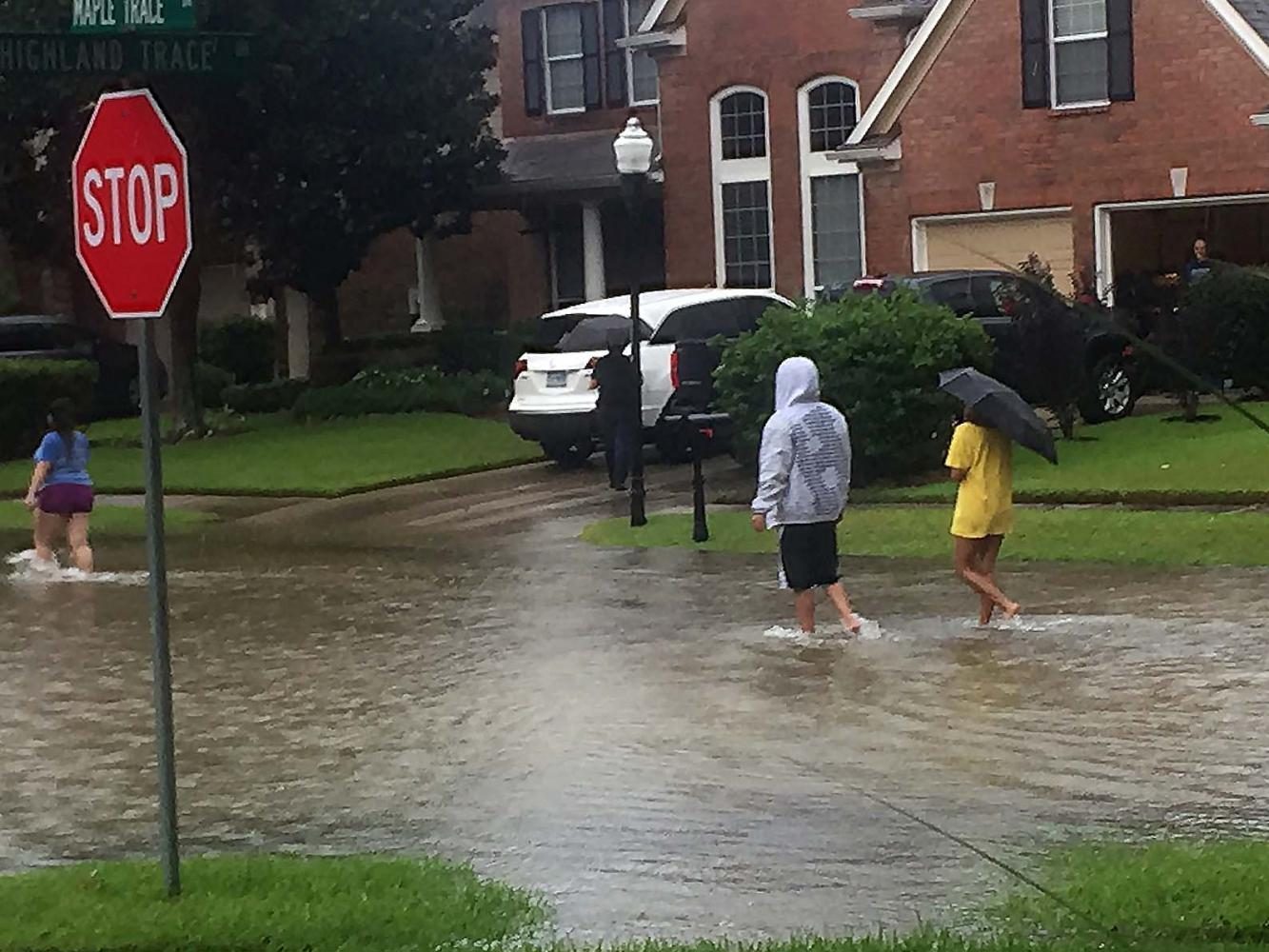 People wade through the water in a flooded neighborhood. “I felt so bad for the homeowners. Helping them out was probably the best thing I could do,” McClain said. “I’m just glad they’re alive.”