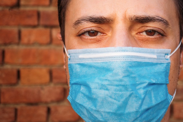 Close-up of a man with a medical face mask. Tight portrait shot with eye contact by Ivan Radic is licensed under CC BY 2.0